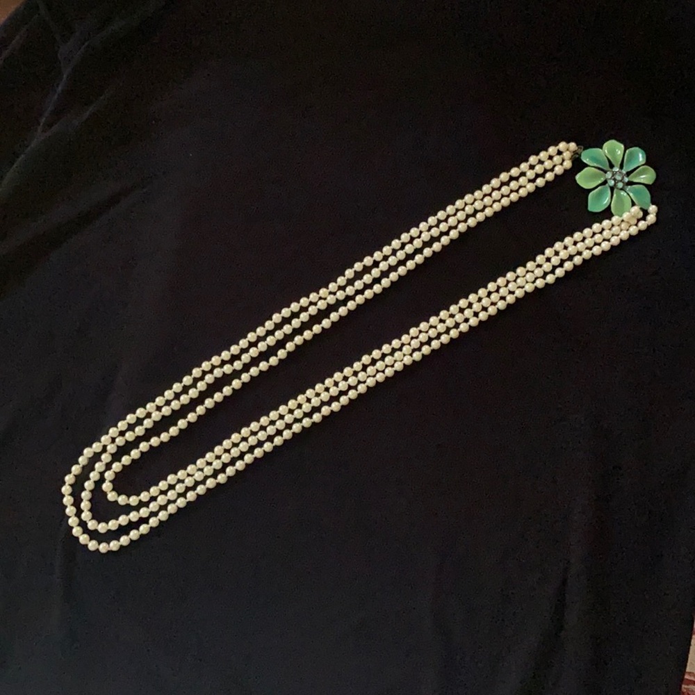 Three-strand pearls with enameled flower accent.